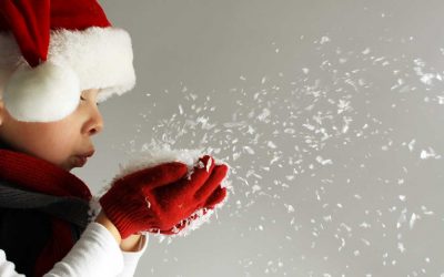 boy with Santa hat and gloves blowing snow